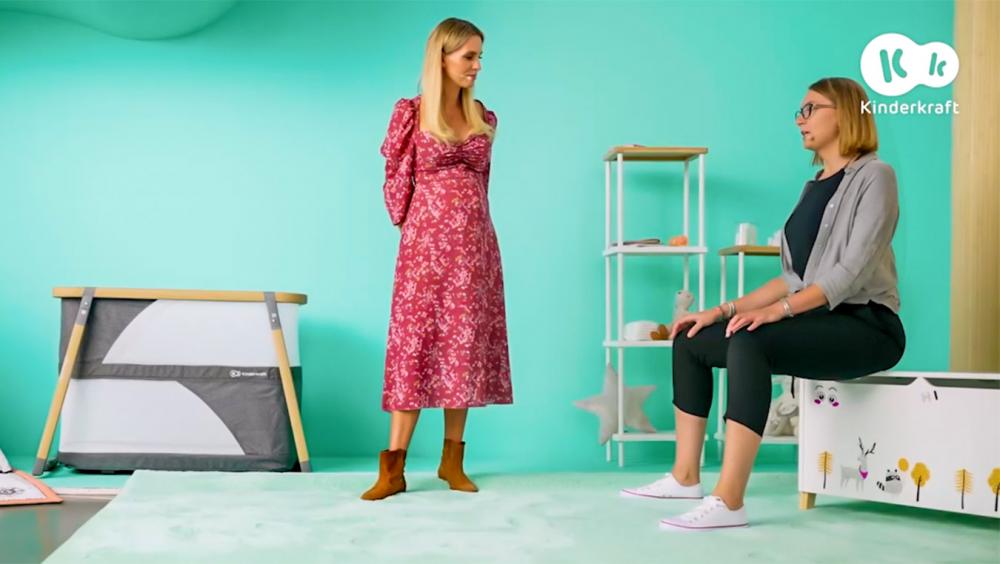 Two women in child's room with mint background, one womand standing and the other one sitting on a toy chest