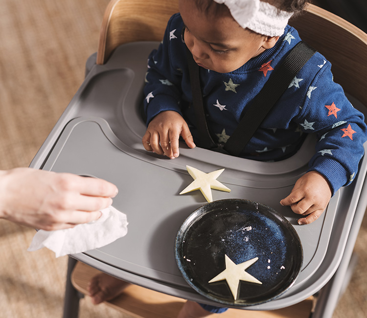 A little girl is sitting in the multifunctional Kinderkraft chair with a table, decorating cookies.