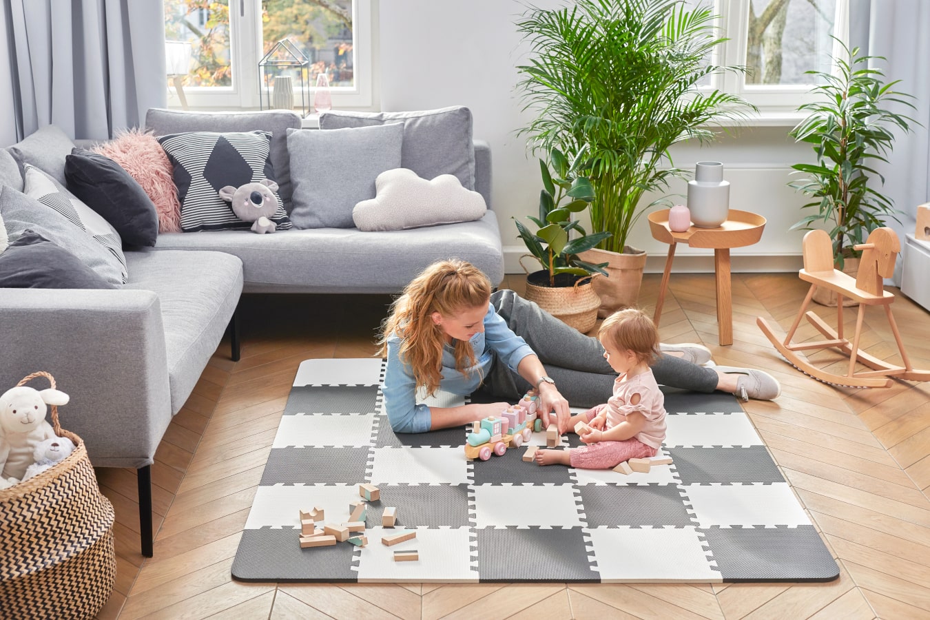 Mum with a small girl together in the living room playing on the luno educational mat.  