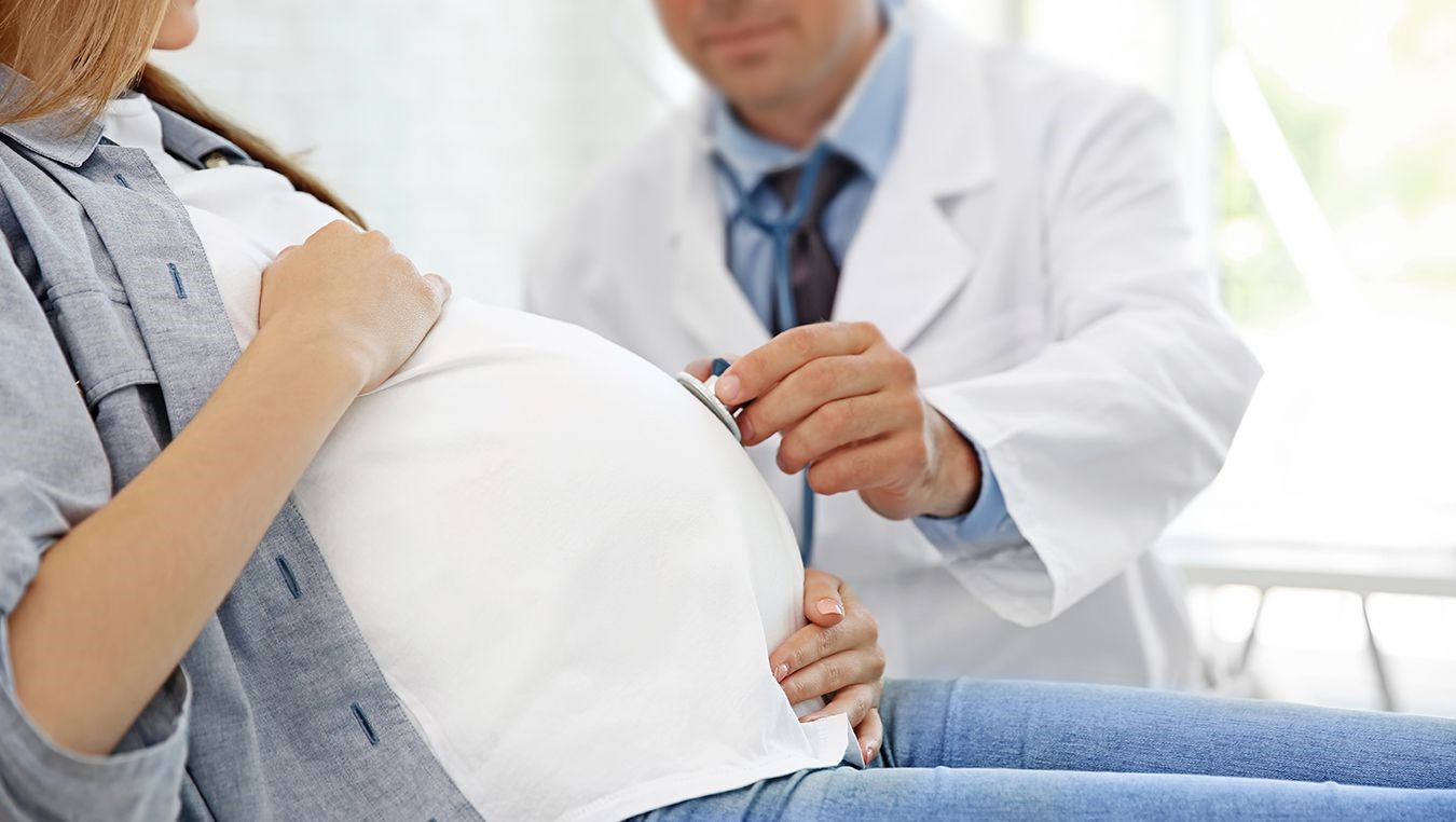 Doctor checking the belly of a pregnant patient with a stethoscope