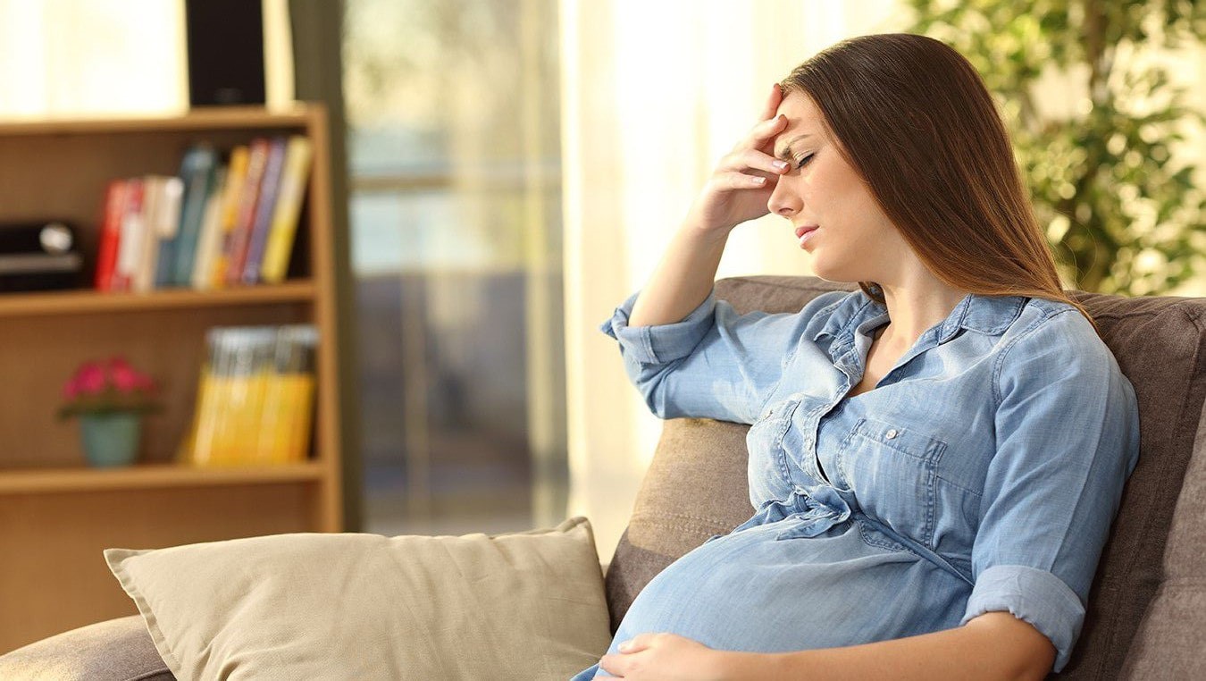 Pregnant woman with a headache holding her head