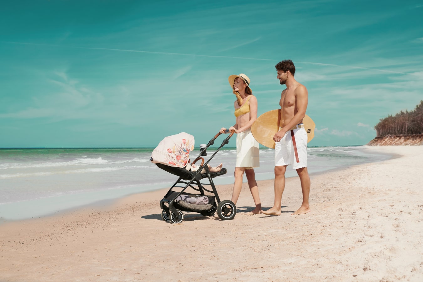 Mum and dad walking along the seashore with a child lying down in the freedom allroad stroller. 